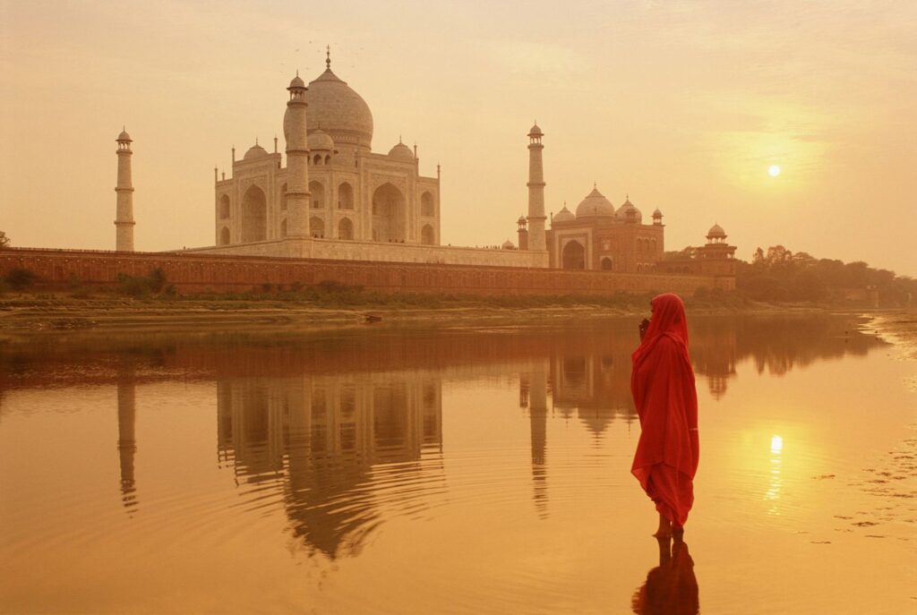 Traveler beside the Taj Mahal reflecting pool at sunrise